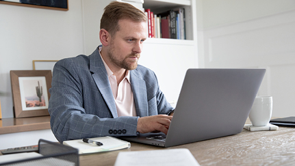 Man sitting behind a desk and working on a laptop.